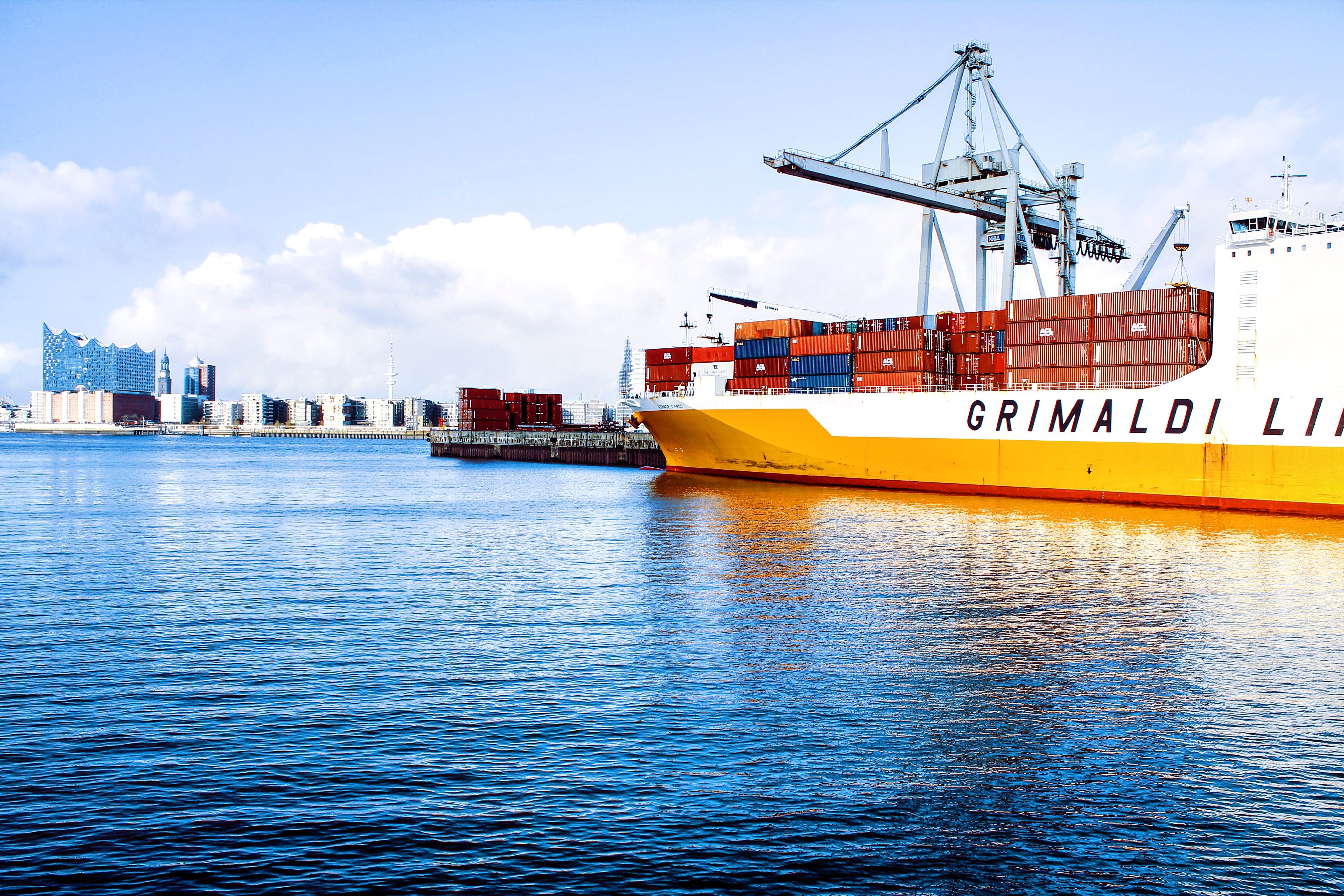 white and orange cargo ship with metal lifting equipment